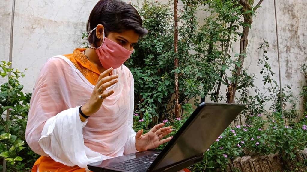 Women in face covering using a laptop